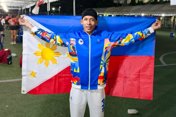 Alfred Talplacido, a proud athlete from La Paz, Tarlac, beams with the Philippine flag after winning gold in the 4x400m relay at the 2026 Singapore Open Track & Field Championships.
